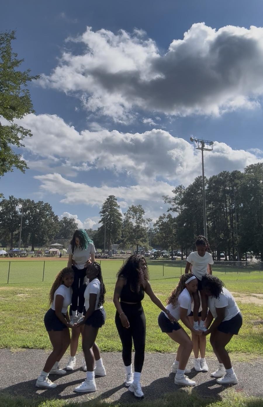 Athletes building two stunts with a coach spotting in the middle