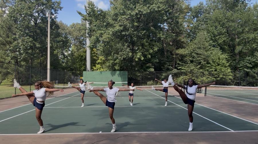 Cheer Lab athletes performing high kicks together on the court