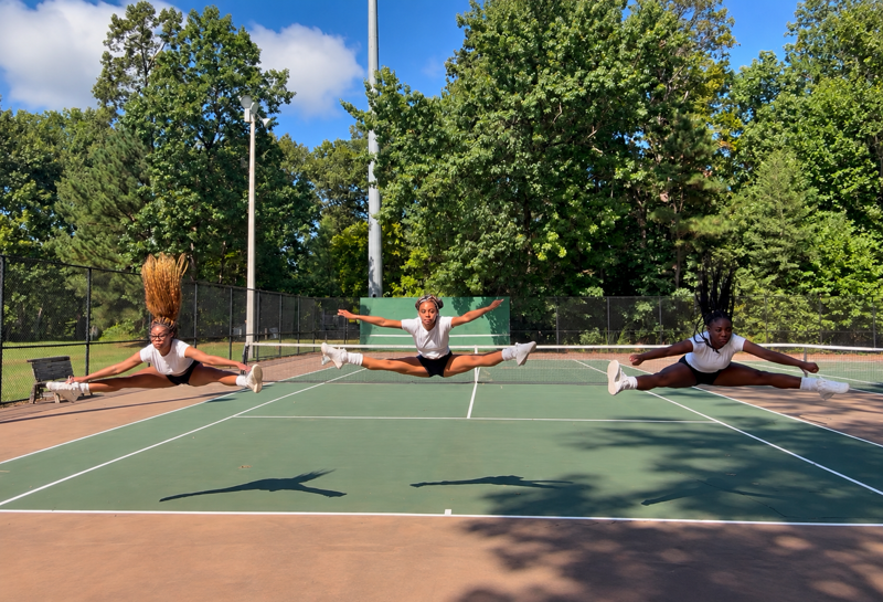 Three Cheer Lab athletes hitting toe-touch jumps in sync on an outdoor court